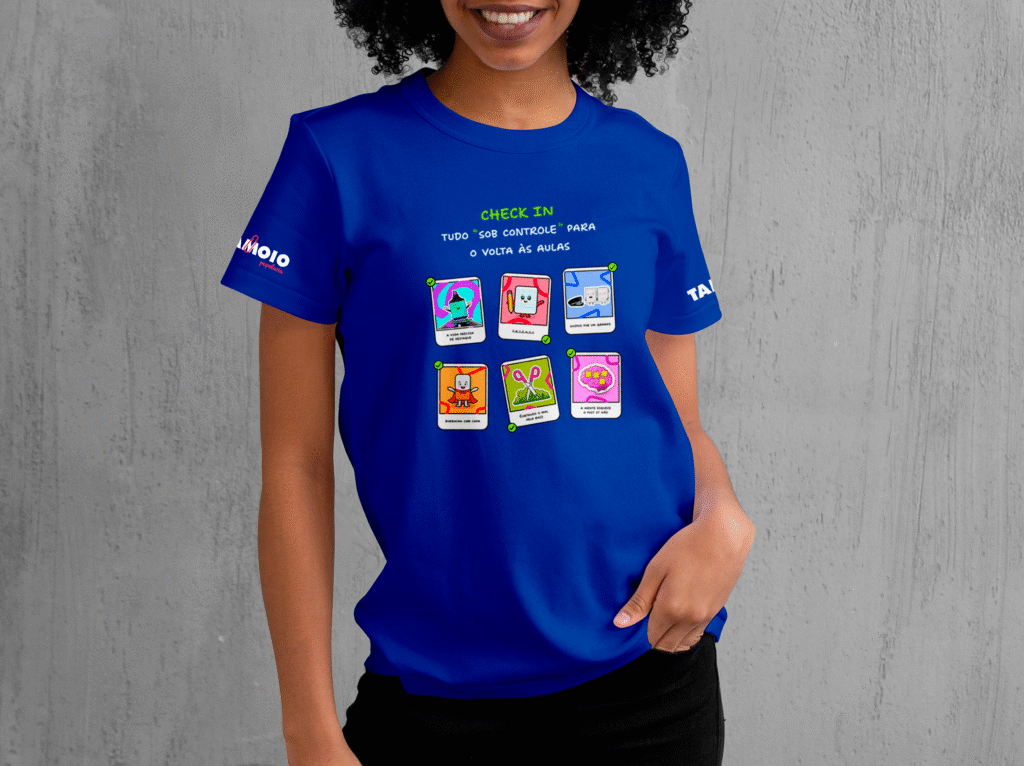 Modelo vestindo camiseta azul royal com estampa criativa "Check In - Tudo Sob Controle", contendo ícones ilustrados de material escolar como borracha e caderno.